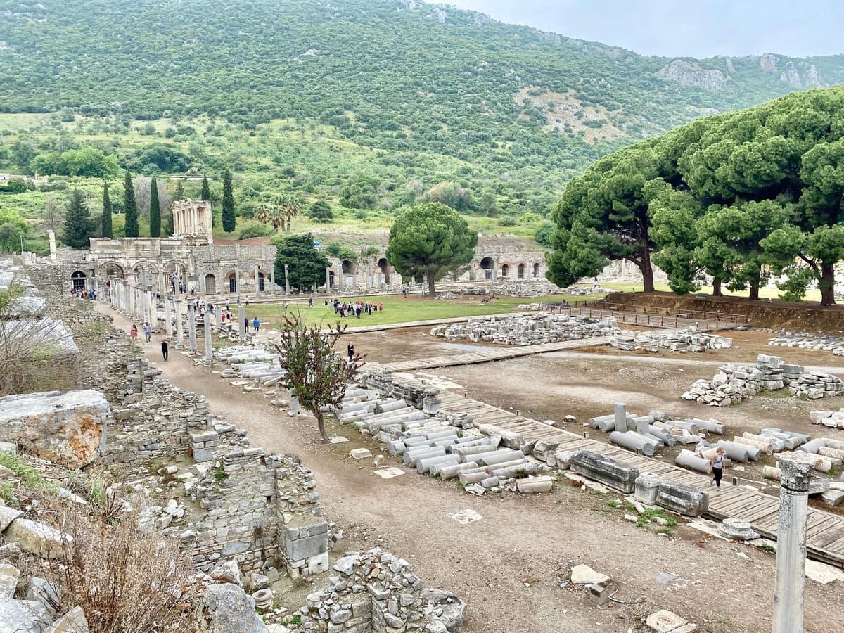 The Commercial Agora of Ephesus seen from above, a wide square of fallen columns and walkways with the Mazeus and Mithridates Gate and the Library of Celsus beyond