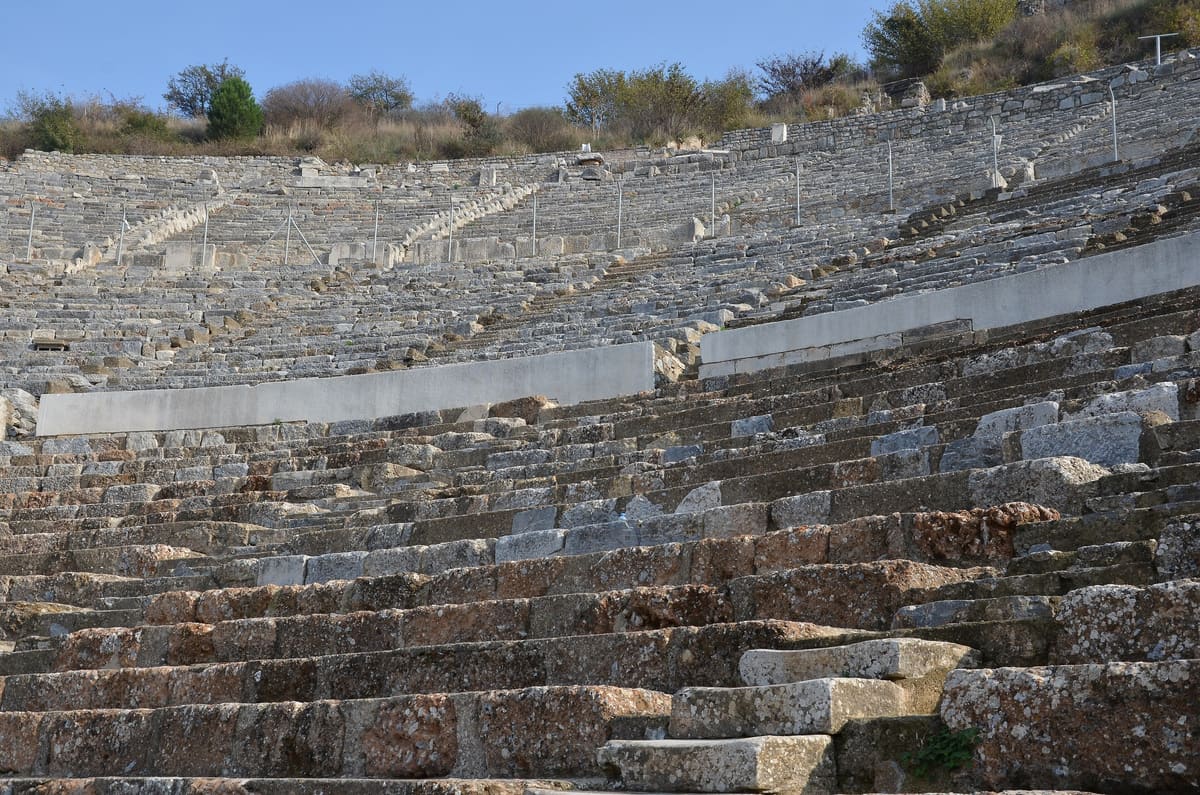 Rows of worn stone seats in the Great Theater of Ephesus, seen from the lower tiers looking up toward the top of the bowl