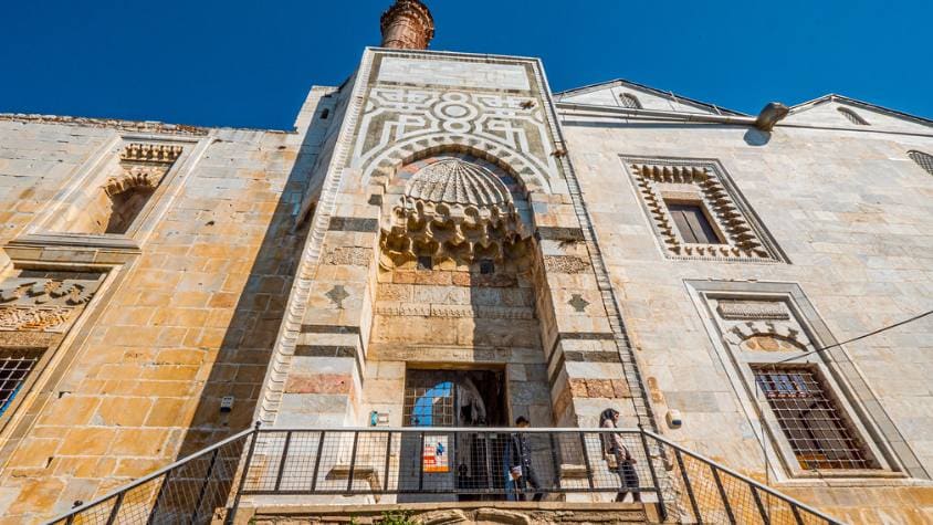 The carved marble entrance portal of the Isa Bey Mosque in Selcuk seen from below against a blue sky